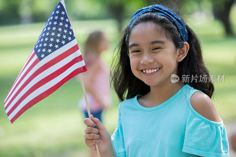 小学年龄的亚洲小女孩微笑着举着美国国旗