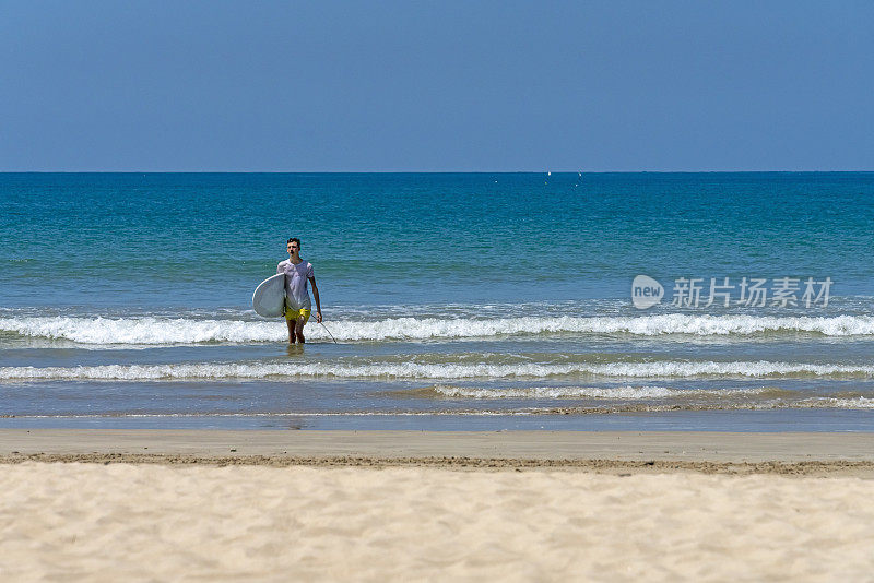 一个年轻人带着冲浪板离开帕卡朗海滩