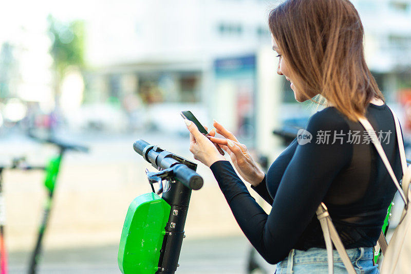 一名女子用手机应用程序解锁一辆电动滑板车