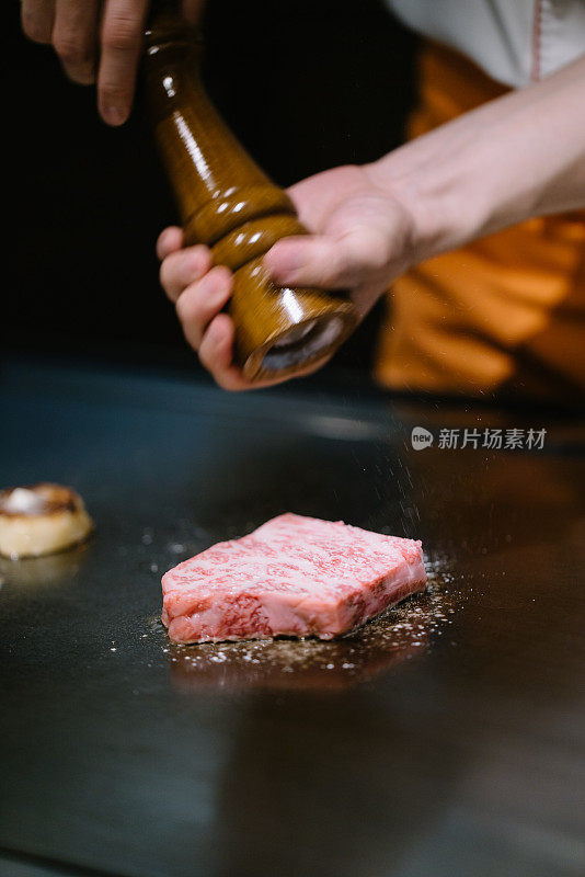 厨师在大理石牛肉上撒盐和胡椒