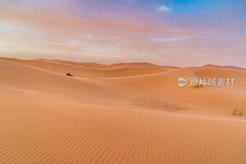 摩洛哥梅尔佐加沙漠中巨大的橙色沙状沙丘和多云的天空。撒哈拉沙漠的日落。
