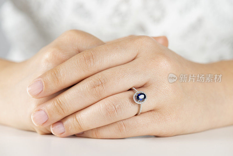 蓝宝石订婚戒指的女人手