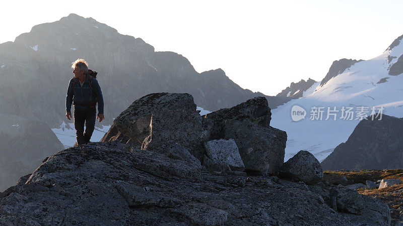 登山者在日出时徒步爬上岩石的顶峰