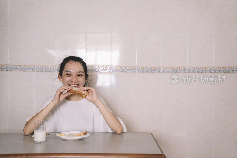 一位亚洲华人女性在厨房里独自吃早餐