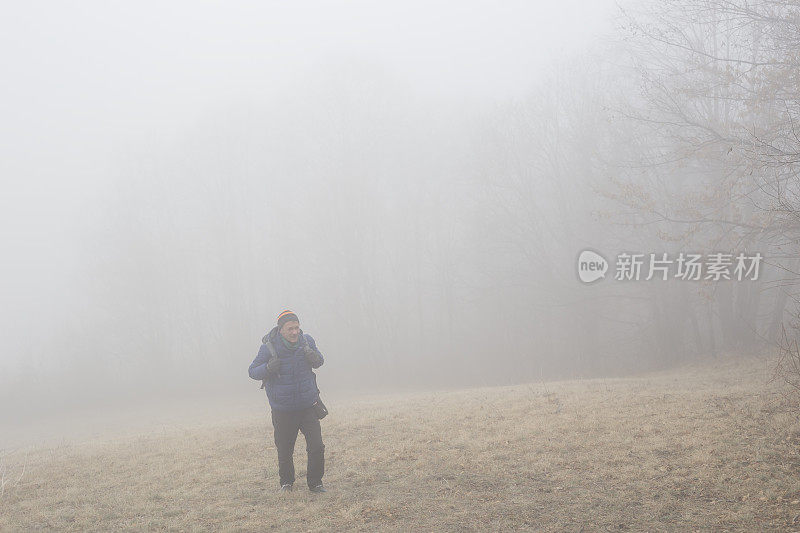 一名成年男子在寒冷多雾的日子徒步旅行