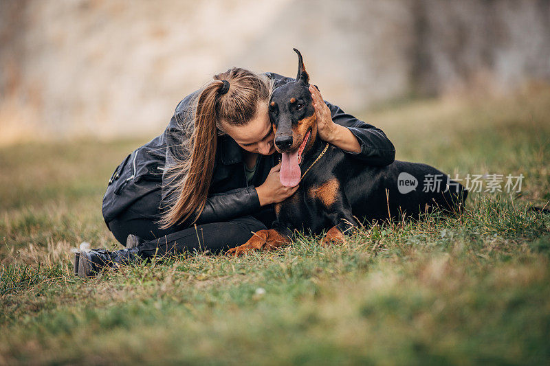 一个女人在公园里和她的杜宾犬玩耍