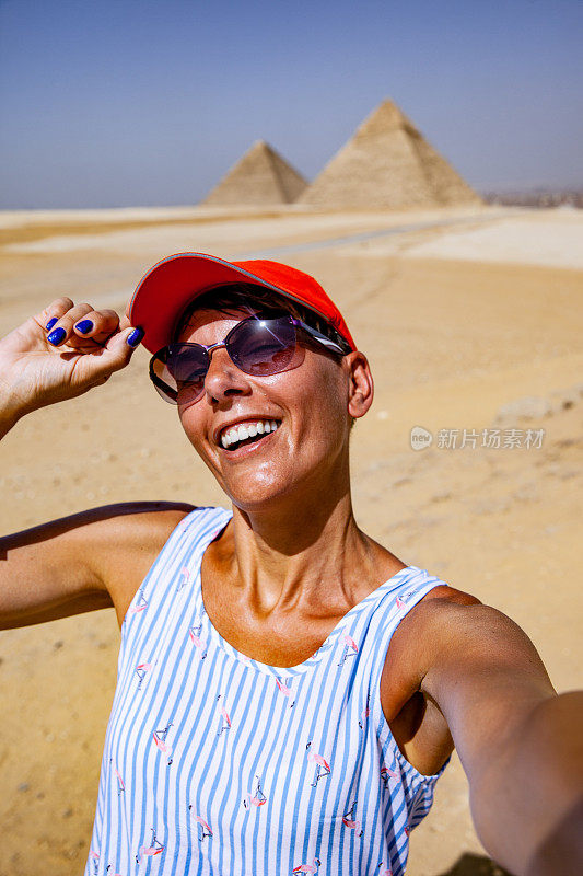成年女子以吉萨金字塔为背景，微笑着自拍