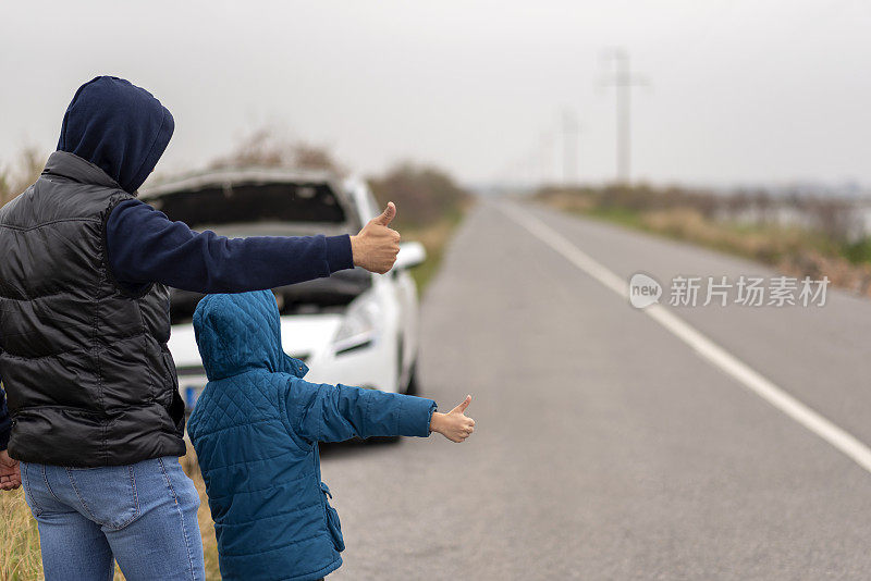 一个无助的男人和他的儿子在车旁