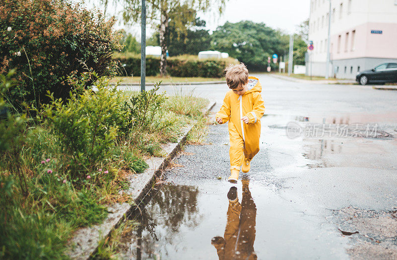 小男孩在雨中玩耍，跳进水里画画