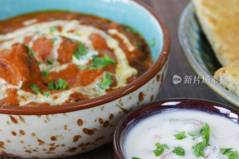 这是一碗自制的咖喱鸡，配上印度烤饼和raita(酸奶酱)的特写画面