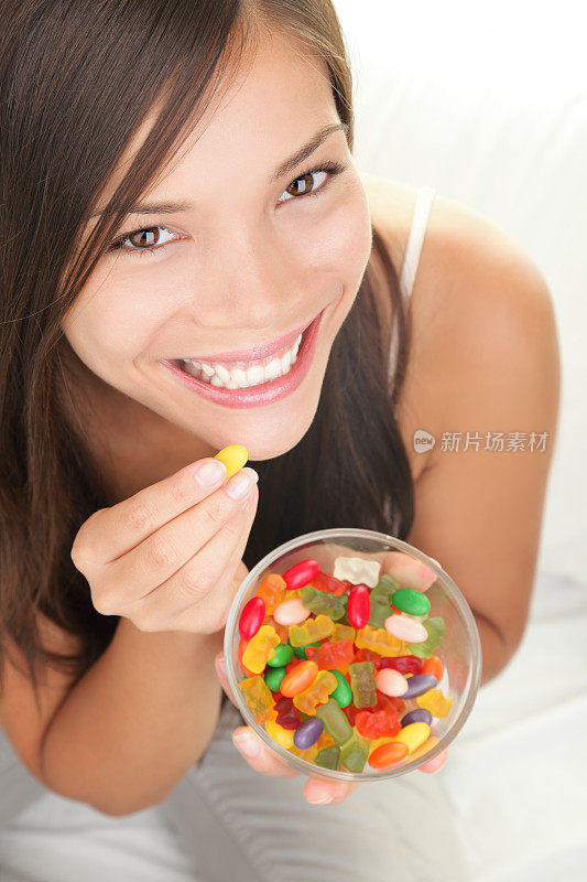 一个女人正在吃彩色的果冻和从玻璃杯里取出的豆子
