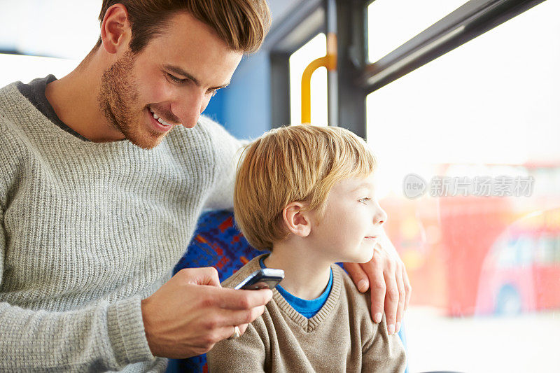父亲和儿子在公车上玩手机