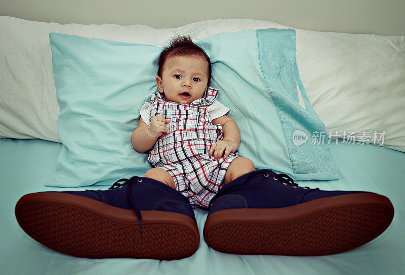 亚洲婴儿穿着大鞋在床上