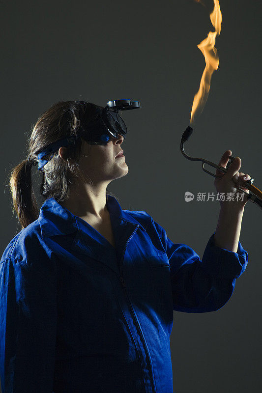 女焊工看着火焰火炬。