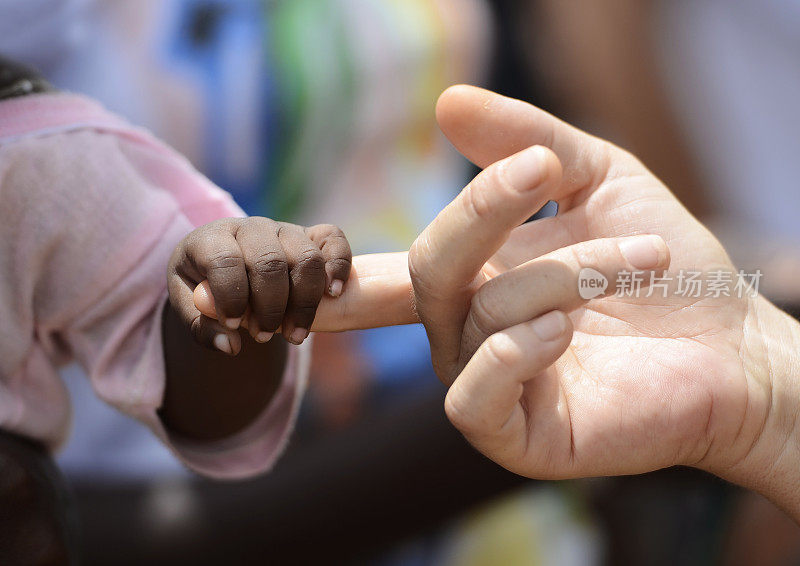 黑人婴儿和白人妇女牵手手指非洲