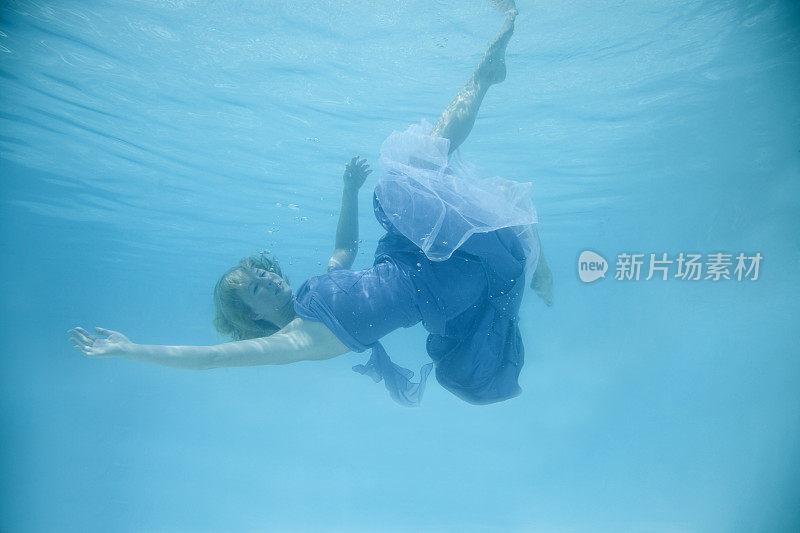 一个穿着裙子在水下游泳的女人。