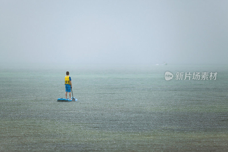 一个男孩在雨中使用划桨板