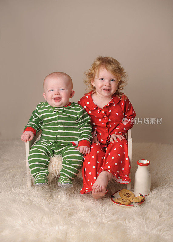 弟弟和妹妹穿着圣诞睡衣坐在木床上