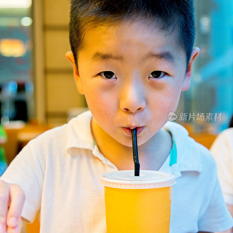 小男孩用吸管喝果汁