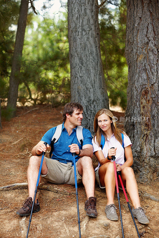 一对夫妇靠着树坐着，从徒步旅行中休息