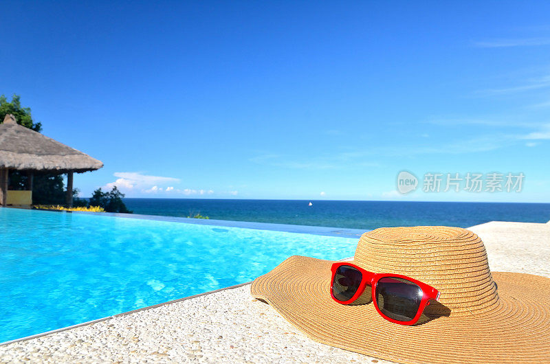 无边泳池边的太阳帽和太阳镜