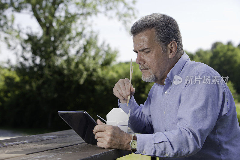 成熟的白种人在午餐时使用数码平板电脑