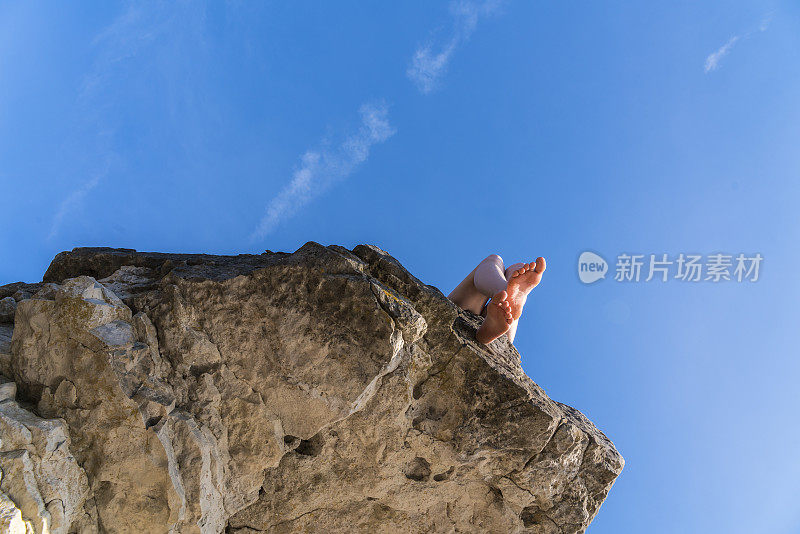 十几岁的女孩坐在悬崖边上，俯视山下。