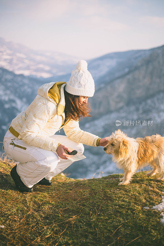 一个女人带着狗在雪地里走在村里的街道上