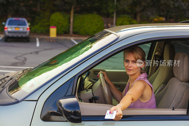 一位女士正在把她的停车卡插入车位
