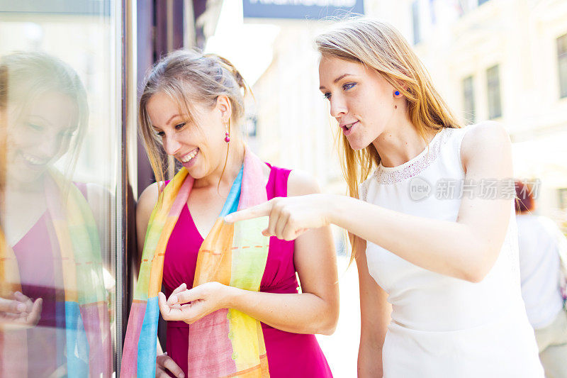 年轻的女人看着街上的商店橱窗