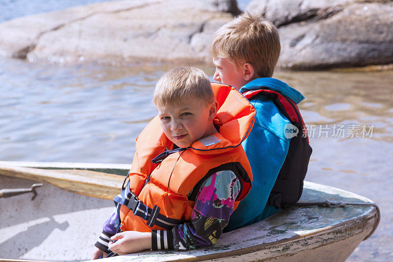 两个穿着救生衣的小男孩在一艘小船上。