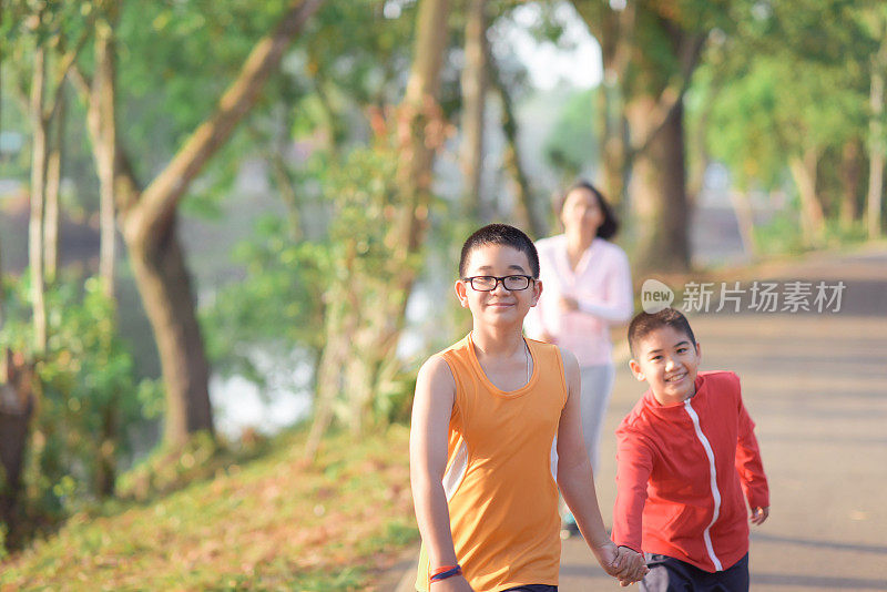 家庭运动快乐活跃的母亲和孩子在户外慢跑，在森林里跑步