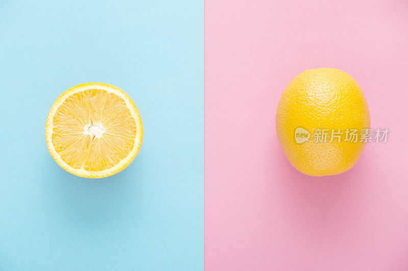 多汁，新鲜，成熟的橙果一个和一个半在玫瑰石英和宁静的蓝色背景。正上方的观点。