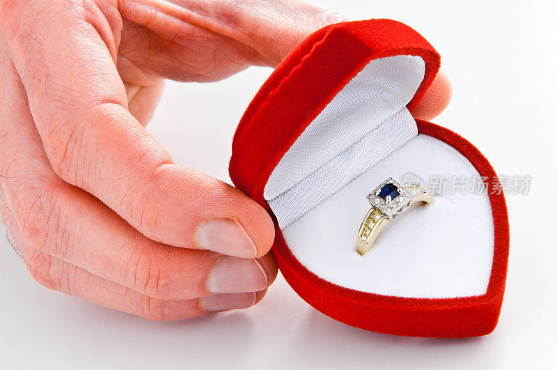 特写男子的手给金订婚戒指，钻石，蓝宝石