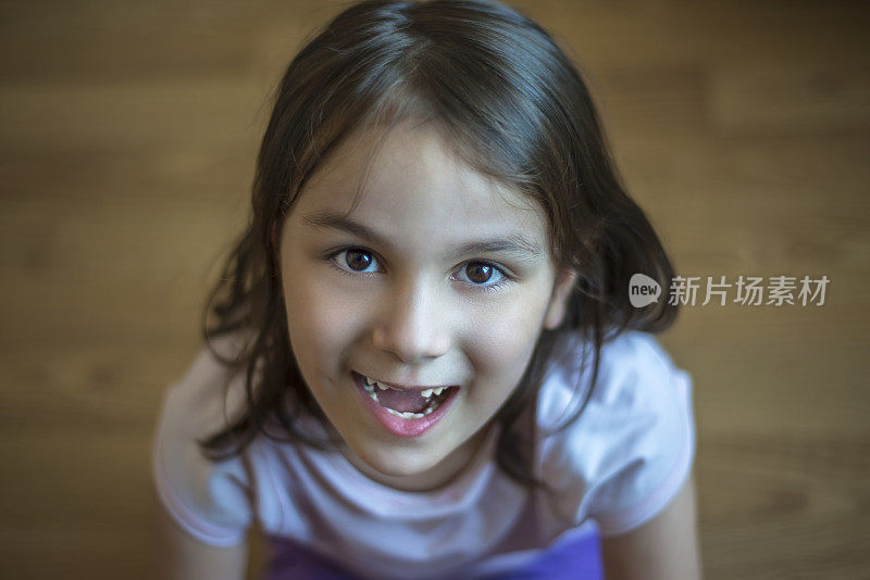 高角度的一个快乐的小女孩看着镜头与牙齿的微笑