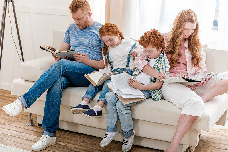 漂亮的红发家庭围坐在沙发上一起看书，大全家福