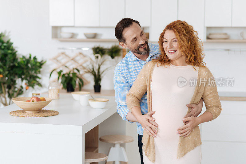 丈夫拥抱他怀孕的妻子