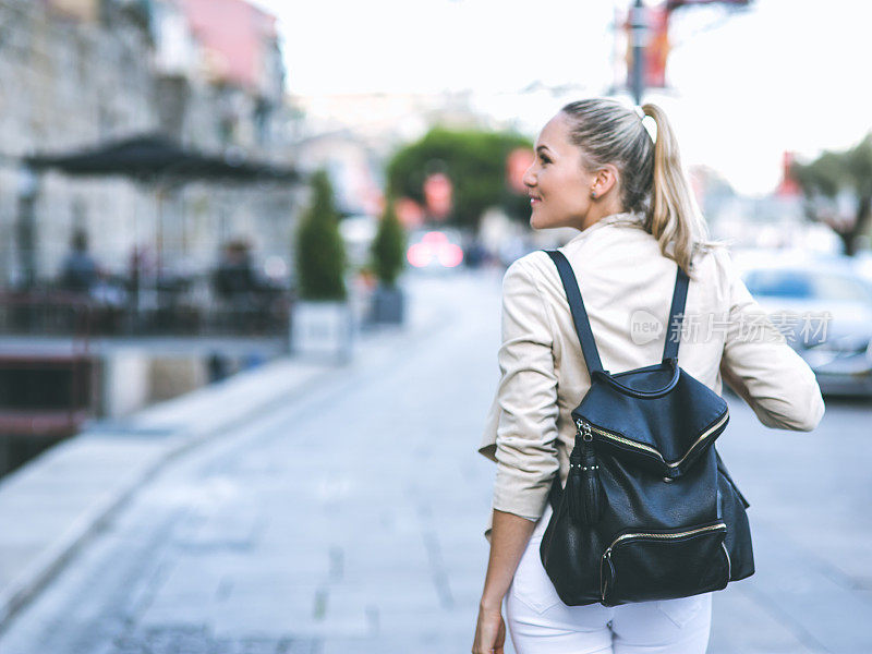 年轻女子背着背包走在欧洲的街道上
