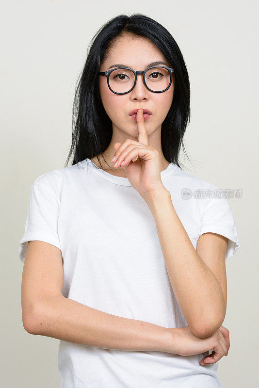 年轻美丽的亚洲女人穿着白色衬衫对抗白色背景