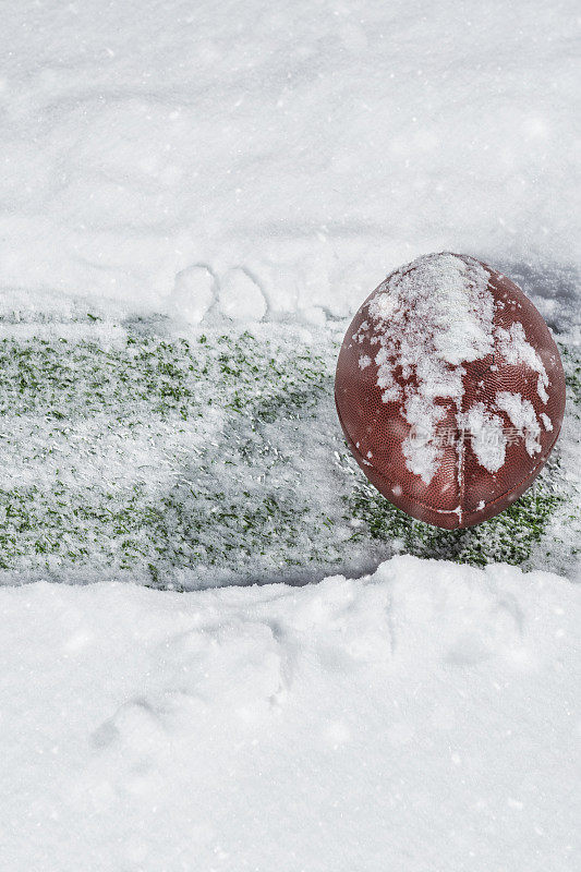 一个美式足球坐在雪地里的院子线上