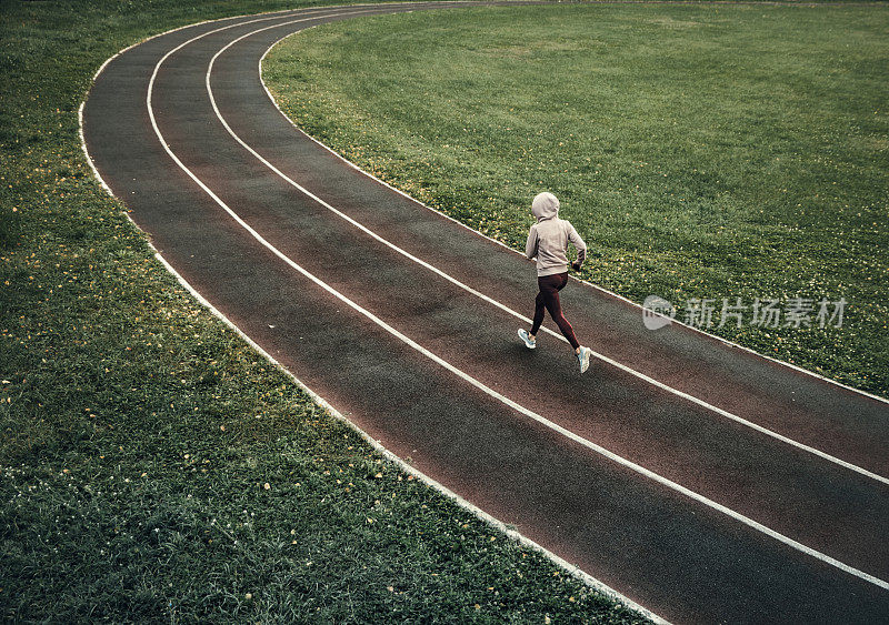 在体育场跑道上跑步的女人