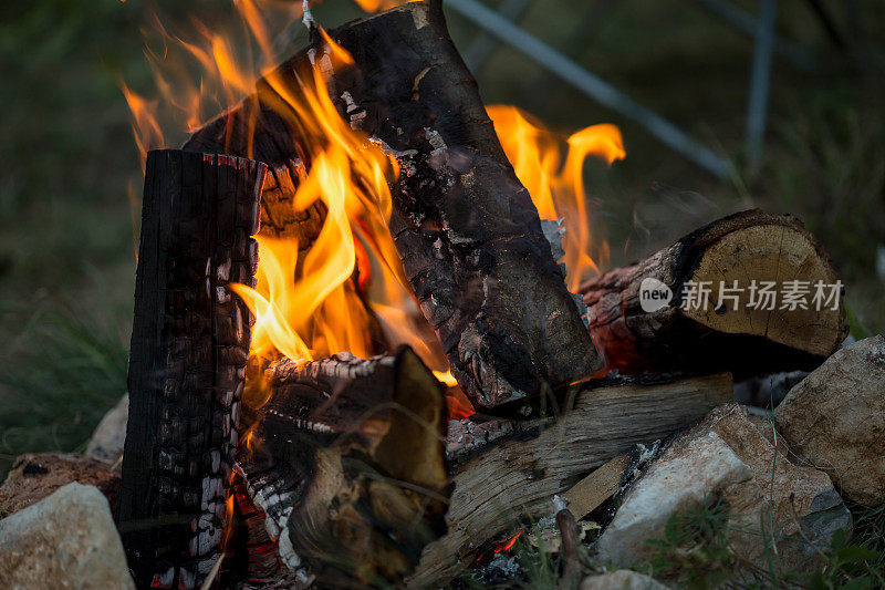 漂亮的一对，围坐在篝火旁。背景是一个帐篷，那人用一根棍子弹火。