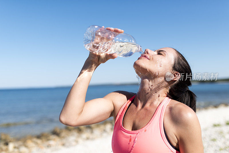 年轻的女运动员把水倒在她的脸上