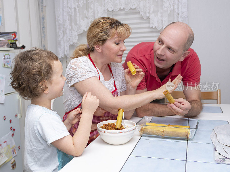 一家人准备食物，意大利肉卷。男人，女人，小孩，白种人，在家庭厨房里。