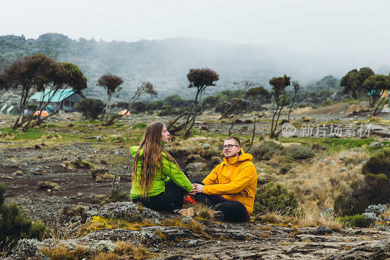 一对年轻的徒步旅行者在通往乞力马扎罗山路上风景优美的营地休息