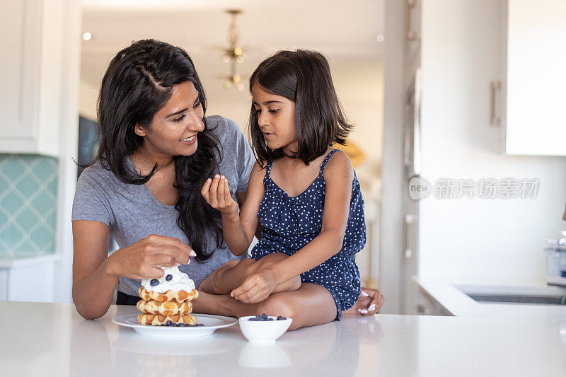 印度母亲与小学年龄的女儿在厨房一起做饭