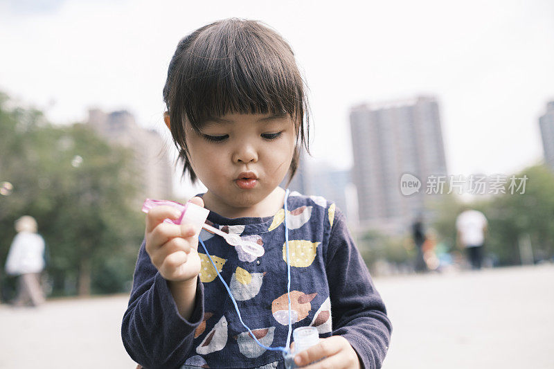 中国小女孩在公园里吹泡泡