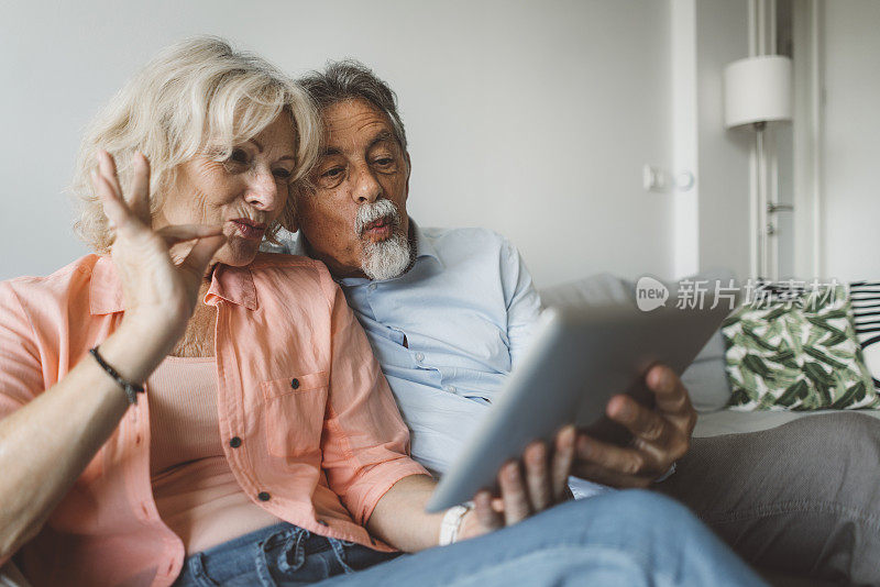 一对老年夫妇手持平板电脑，与家人视频通话