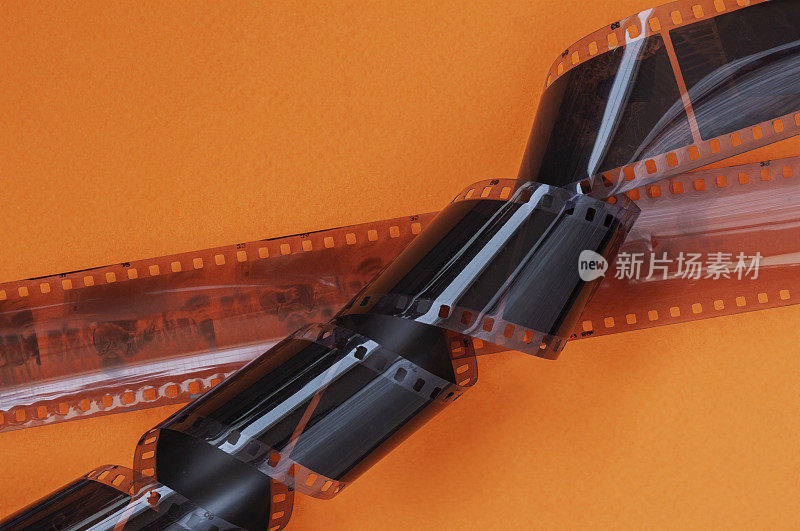 旧的35毫米摄影胶片条，在明亮的橙色背景上负片，平铺。照片、电影、电影概念