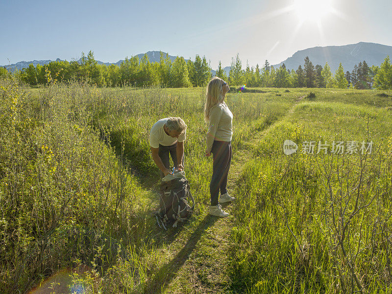 徒步旅行的夫妇沿着小路穿过绿色的山地草地